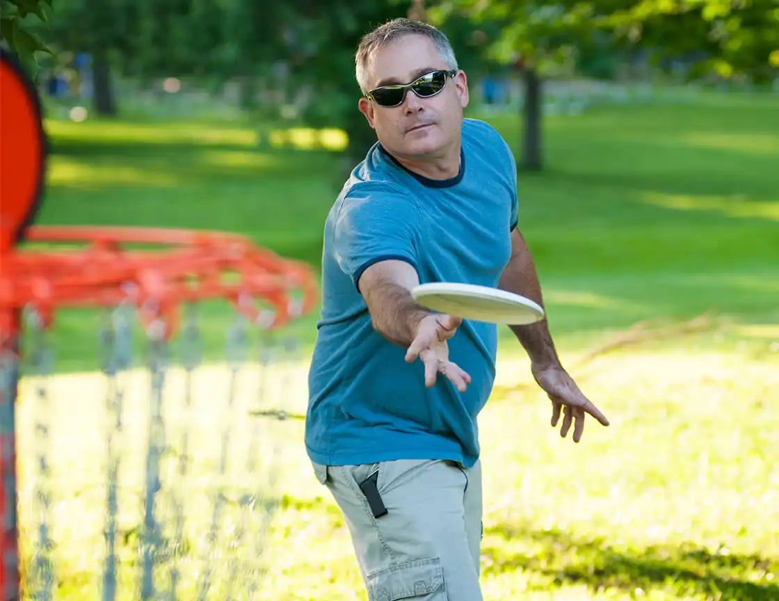 An older man playing on a disc golf team.